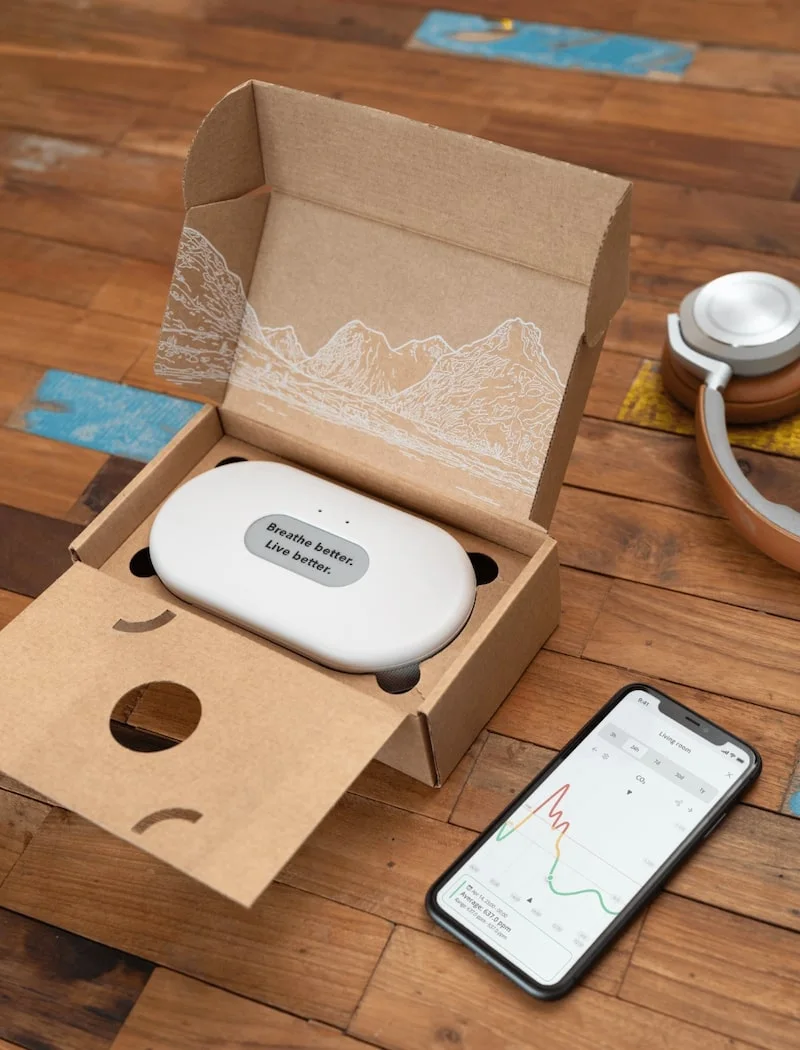 Airthings View Plus air quality monitor standing on a wooden kitchen counter.