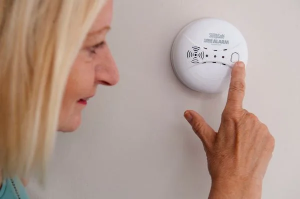 First Alert CO710 carbon monoxide alarm sitting on a hallway shelf with its digital display visible.
